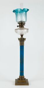 An antique kerosene banquet lamp, blue and gilt porcelain Corinthian column base with brass base and capital, cut crystal font, black button double burner with original blue acid etched glass shade and later chimney, 19th century, an impressive 107cm high