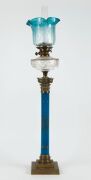 An antique kerosene banquet lamp, blue and gilt porcelain Corinthian column base with brass base and capital, cut crystal font, black button double burner with original blue acid etched glass shade and later chimney, 19th century, an impressive 107cm high