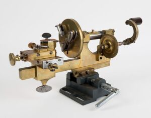 An antique English hand operated watchmaker's lathe with cross slide and adjustable face plate, 19th century, 21cm high, 43cm wide