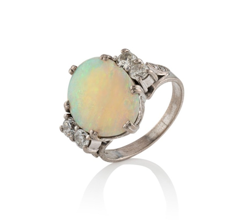 A platinum ring, set with a solid Coober Pedy white opal, flanked by two pairs of brilliant cut white diamonds, 6.9 grams total