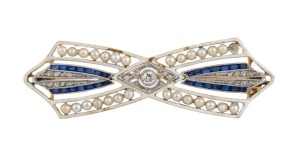 An antique French 18ct gold brooch, set with diamonds, seed pearls and sapphires, adorned with white enamel, circa 1900, ​​​​​​​4.6 cm wide, 6 grams