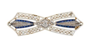 An antique French 18ct gold brooch, set with diamonds, seed pearls and sapphires, adorned with white enamel, circa 1900, 4.6 cm wide, 6 grams