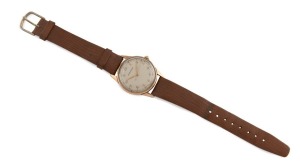 MOVADO manual wristwatch in solid 9ct gold case, silver dial with Arabic numerals and brown leather band, circa 1960. 3.4cm wide including crown