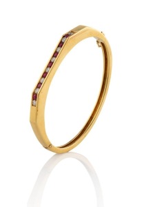 An Art Deco 18ct solid yellow gold bangle, set with a row of alternating rubies and brilliant cut diamonds, 20th century, ​​​​​​​6cm wide (internal 5.5cm wide), 27 grams