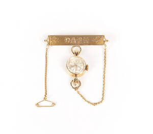 ROLEX: Lady's 18ct gold cased watch on gold bar brooch.