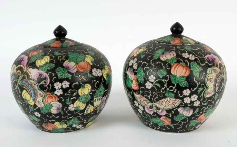 A pair of antique Chinese porcelain lidded jars with butterflies and fruit on black ground, 19th/20th century, red seal mark to bases, ​​​​​​​20cm high, 19cm wide