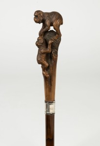 An antique walking stick with carved boxwood monkey handle, silver collar, cane shaft and brass ferrule, 19th century, 88.5cm high