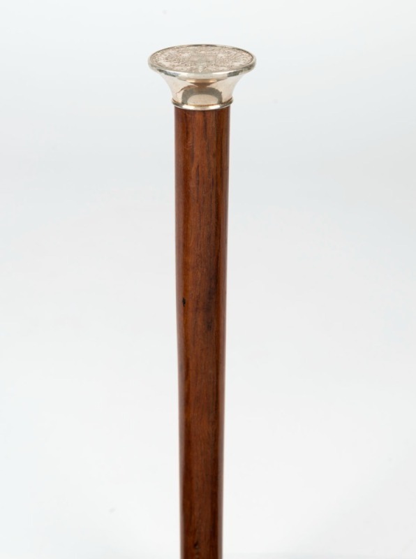 An antique walking stick with silver top inset with an antique Austrian silver coin dated 1780, beefwood shaft and brass ferrule, 19th century, ​​​​​​85cm high