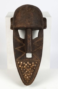 A zoomorphic mask, carved wood, metal and shell, East African origin, 57cm high