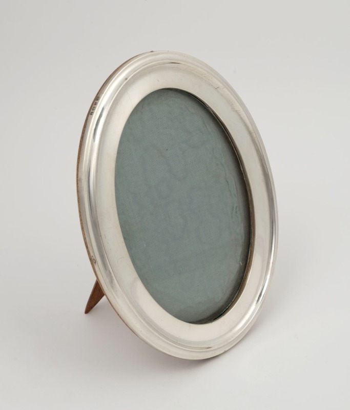 A sterling silver oval table picture frame, made in Birmingham, circa 1914, ​​​​​​​20.5cm high