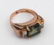 An Art Deco 14ct rose gold ring, set with an emerald cut green sapphire, flanked by a pair of white diamonds, early to mid 20th century, stamped "14K" with pictorial mark, 5.2 grams