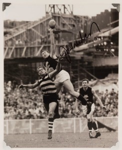 An iconic image from the 1967 Preliminary Final showing John Nicholls soaring above Graham 'Polly' Farmer (Geelong) and team-mate, Ron Barassi; signed by Nicholls. 25 x 20cm.