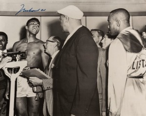 Muhammad Ali, signed b/w photograph of Ali at weigh-in with Sonny Liston, 41 x 51cm. Muhammad Ali (then known as Cassius Clay) taunts Sonny Liston during their weigh-in before the World Heavyweight Title fight on 25th February 1964. Clay won, in a seventh round TKO.