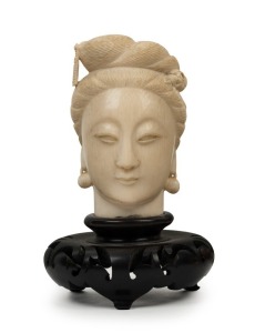 An antique Japanese carved ivory bust of a lady's face, on later wooden stand, Meiji period, 19th century, the bust 9.5cm high, 13.5cm high overall