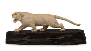 An antique Japanese carved ivory tiger statue with mother of pearl inlaid eyes and carved timber base, Meiji period, 19th century, seal mark to rear paw, ​​​​​​​13cm long