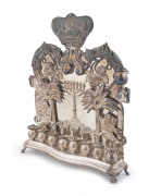 A silver plate Hannukah oil lamp of Polish origin, decorated with a menorah, applied figures of rampant lions, palm trees and leaves beneath a Torah crown, made by Norblin & Co, Warsaw, early 20th century, (lacks one perforated burner cover), 29cm high. - 2