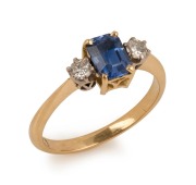 An antique 18ct yellow gold ring, set with an emerald cut Ceylonese sapphire, flanked by brilliant cut white diamonds, early 20th century, ​​​​​​​2.9 grams total