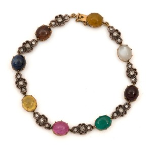 An Edwardian multi-coloured gemstone and diamond bracelet mounted in 18ct yellow gold and platinum, circa 1910. Set with cabochon sapphires, natural emerald, garnet, tourmaline and moonstone. ​​​​​​​18cm long