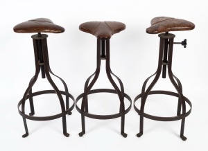 A set of three iron and leather saddle topped bar stools,  ​​​​​​​76cm high 