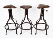 A set of three iron and leather saddle topped bar stools,&nbsp; ​​​​​​​76cm high&nbsp;