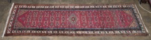 A Persian hand-knotted wool runner with crimson ground, 298 x 87cm