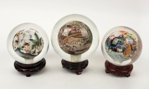 Three Chinese glass sphere ornaments with internal hand-painted scenes, on timber stands, 20th century, ​​​​​​​the largest 16cm high overall