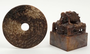 A Chinese carved stone bi disc and a stone seal with dragon decoration, unknown age, the disc 14cm diameter