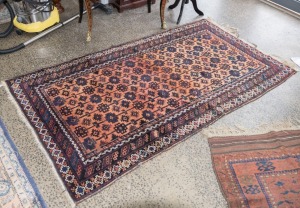 A hand-knotted tribal rug with brown and orange ground (fair condition only), 213 x 118cm