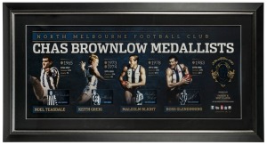 North Melbourne FC signed Brownlow official print with replica Brownlow Medal. Limited edition #54 of 200. Signed by Noel Teasdale, Keith Greig, Malcolm Blight and Ross Glendinning. Official AFLPA CoA included. 56 x 105cm overall