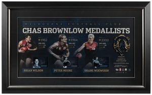 Melbourne FC signed Brownlow official print with replica Brownlow Medal. Limited edition #3 of 200. Brian Wilson. Peter Moore and Shane Woewodin. Official AFLPA CoA included. ​​​​​​​53 x 85cm overall