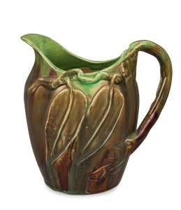 REMUED pottery jug with applied gum leaves and branch handle, glazed in green and brown with a blush of pink, incised "Remued", 17.5cm high