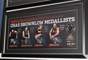 Essendon Football Club signed Brownlow official print with replica Brownlow Medal (limited edition #20 of 200), signed by Graham Moss, Gavin Wanganeen, James Hird and Jobe Watson. Official AFLPA COA included. Framed: 56 x 104cm.