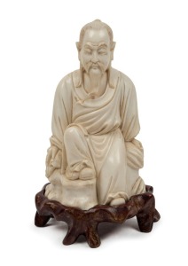 A Chinese carved ivory statue of a seated scholar, with carved wooden stand, 19th/20th century, 15cm high overall