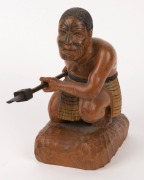 A carved statue of a crouching Maori warrior with taiaha and full Tā moko, 20th century, 20.1cm high - 2