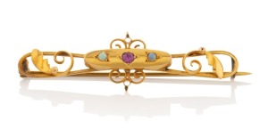 An antique Australian yellow gold bar brooch adorned with a ruby flanked by two polished opals, 19th century, 5.5cm wide, 3.1 grams