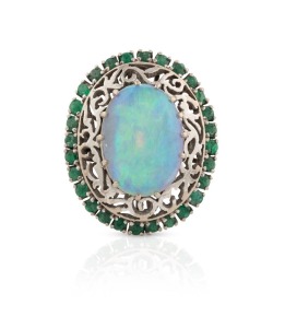 An 18ct white gold ring, set with a stunning large solid cabochon opal, surrounded with pierced gold work with emerald border, mid 20th century, stamped "18ct", 8 grams