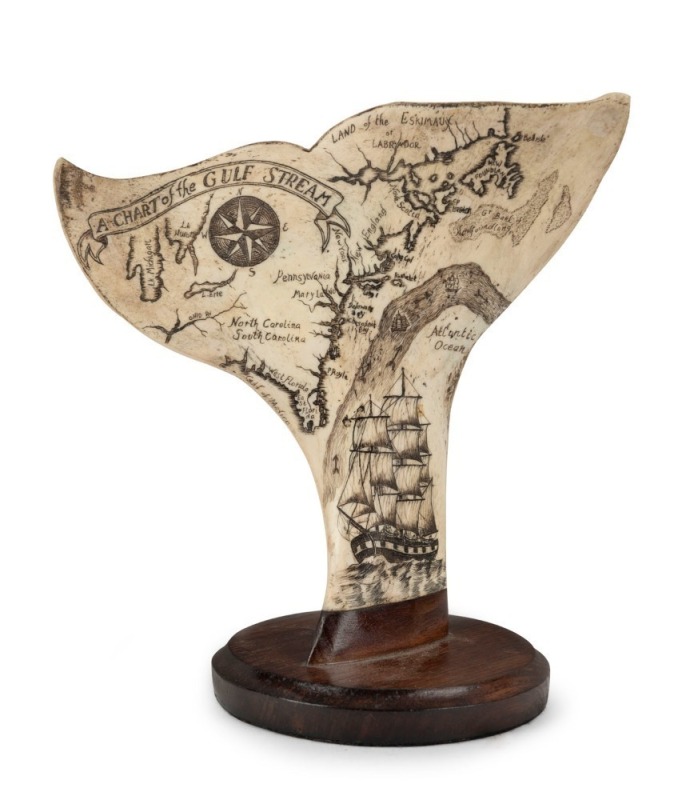 "A CHART OF THE GULF STREAM" scrimshaw whale bone carved into the form of a whale's tail, mounted on blackwood, 21cm high