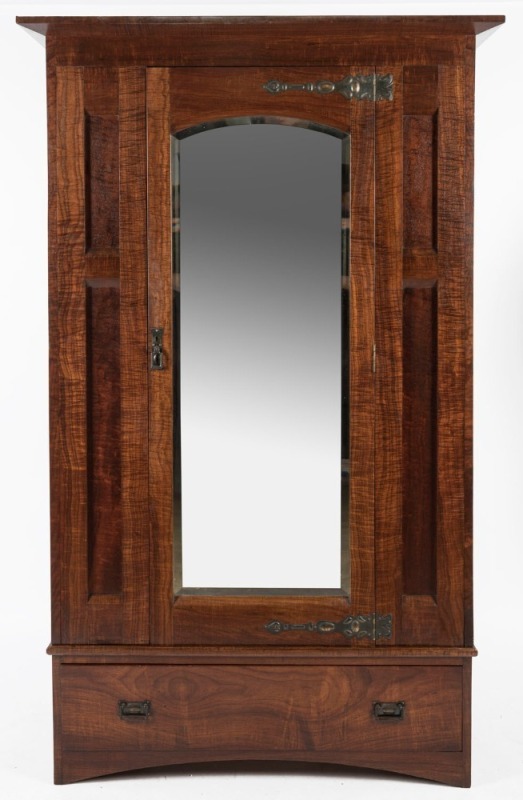 An Australian solid fiddleback blackwood wardrobe with arch-top bevelled mirror door, base drawer and Art Nouveau copper strap hinges, circa 1915. Note: two piece unit. 201cm high, 119cm wide, 53.5cm deep