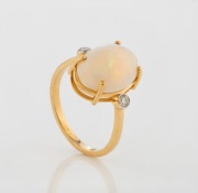 A 9ct yellow gold ring, set with a large polished solid white opal, flanked by two white diamonds, 20th century, stamped "9k", 3.2 grams