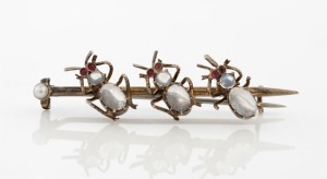 An antique silver gilt brooch adorned with three insects with cabochon moonstone bodies, ruby eyes and seed pearl end, 19th century, 5.5cm wide