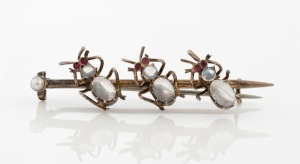 An antique silver gilt brooch adorned with three insects with cabochon moonstone bodies, ruby eyes and seed pearl end, 19th century, ​​​​​​​5.5cm wide