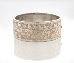 An antique sterling silver bangle with engraved foliate motif, 19th century, 6.5cm wide, band width 2.5cm, 22 grams