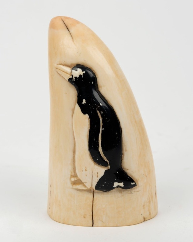 A scrimshaw whale's tooth with penguin carving in high relief, 11cm high