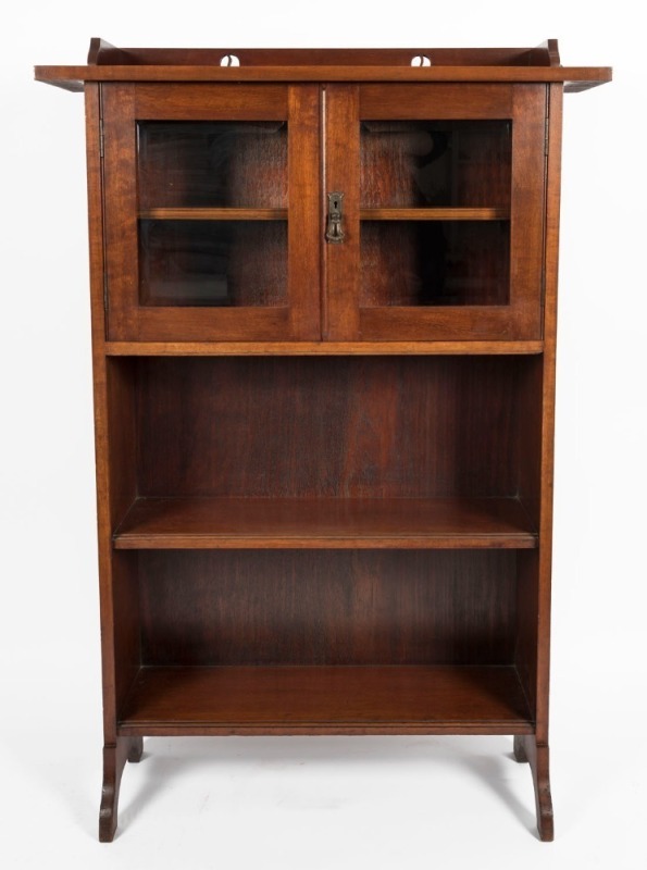 An Australian solid blackwood Arts & Crafts bookcase with pierced rail back, two bevelled glass doors, two lower open tiers and shaped feet, circa 1910, 146cm high, 98.5cm wide, 32cm deep