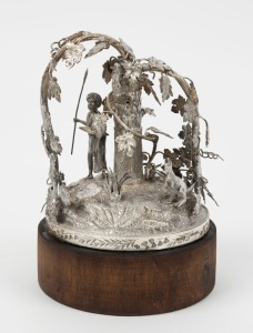 HENRY YOUNG of Melbourne, Australian sterling silver ornament with standing Aboriginal warrior and kangaroo amongst foliage and grasstrees, 19th century. Note: Most likely an incomplete base to an emu egg casket or centrepiece. Mounted on later wooden base. Stamped "H. YOUNG, STG SILVER", Silver piece 12.5cm high, 15.5cm high overall.