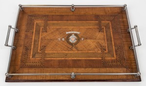 An antique Australian specimen timber marquetry serving tray with metal gallery, presented as a prize with sterling silver and rose gold plaques "THE BEST AND FAIREST, WON BY S.B.F." (South Brisbane Football Club?), Queensland origin, early 20th century, 59cm across the handles