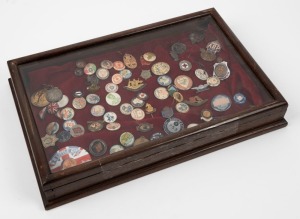 A small desk top display case, containing a diverse range of badges, buttons and pins, mostly military and including a 1914-19 victory medal engraved to a A.I.F. soldier, A.I.F. Returned From Active Service, Ex Prisoners of war association appeal badge, A