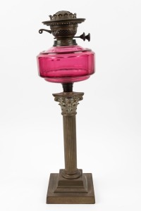 An antique oil lamp with black button double burner, faceted ruby glass font and Corinthian column base, 19th century, 52cm high