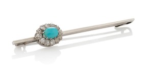 An antique platinum brooch, set with a cabochon turquoise surrounded with twelve impressive white diamonds, circa 1910, 7.5cm wide, 6.5 grams