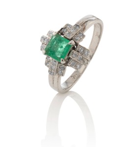 An 18ct white gold ring, set with a cut natural emerald surrounded by diamond clusters, circa 1930s, ​​​​​​​3.3 grams